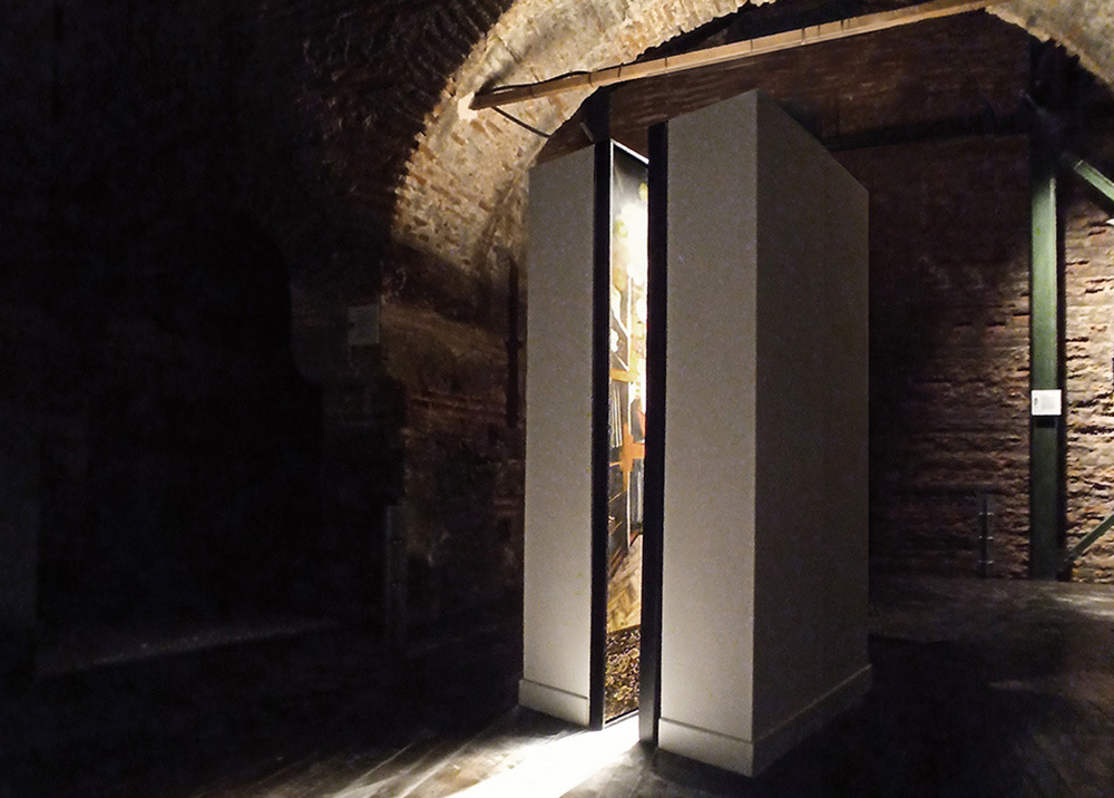 Installation view of Acute Angle showing a painting visible through a narrow architectural aperture flanked by towering panels.